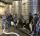The winery crew stands in front of large stainless steel fermentation tanks.